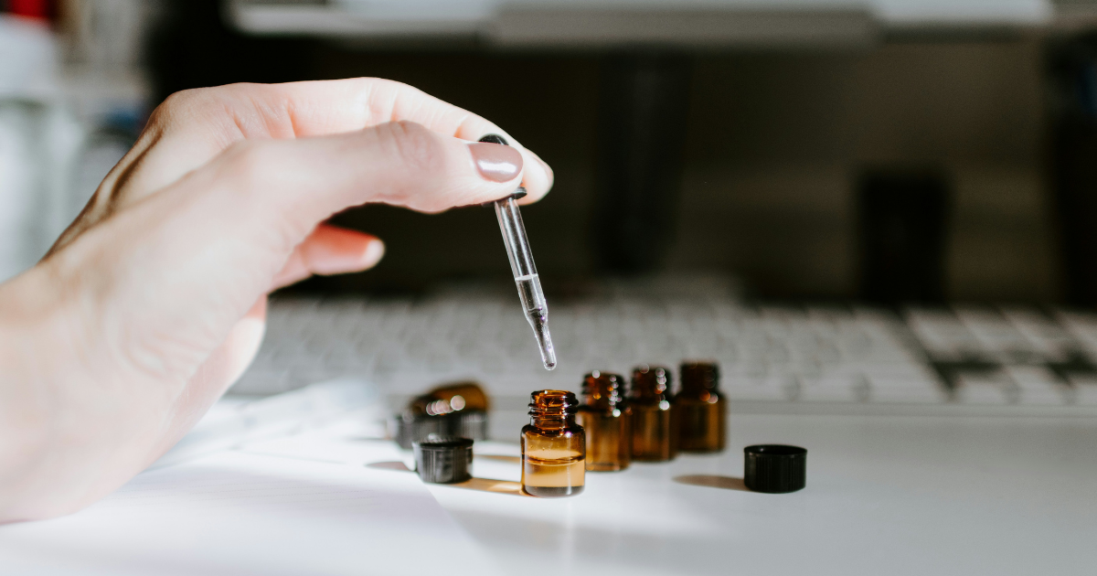 A participant measuring a fragrance material drop by drop into an amber bottle