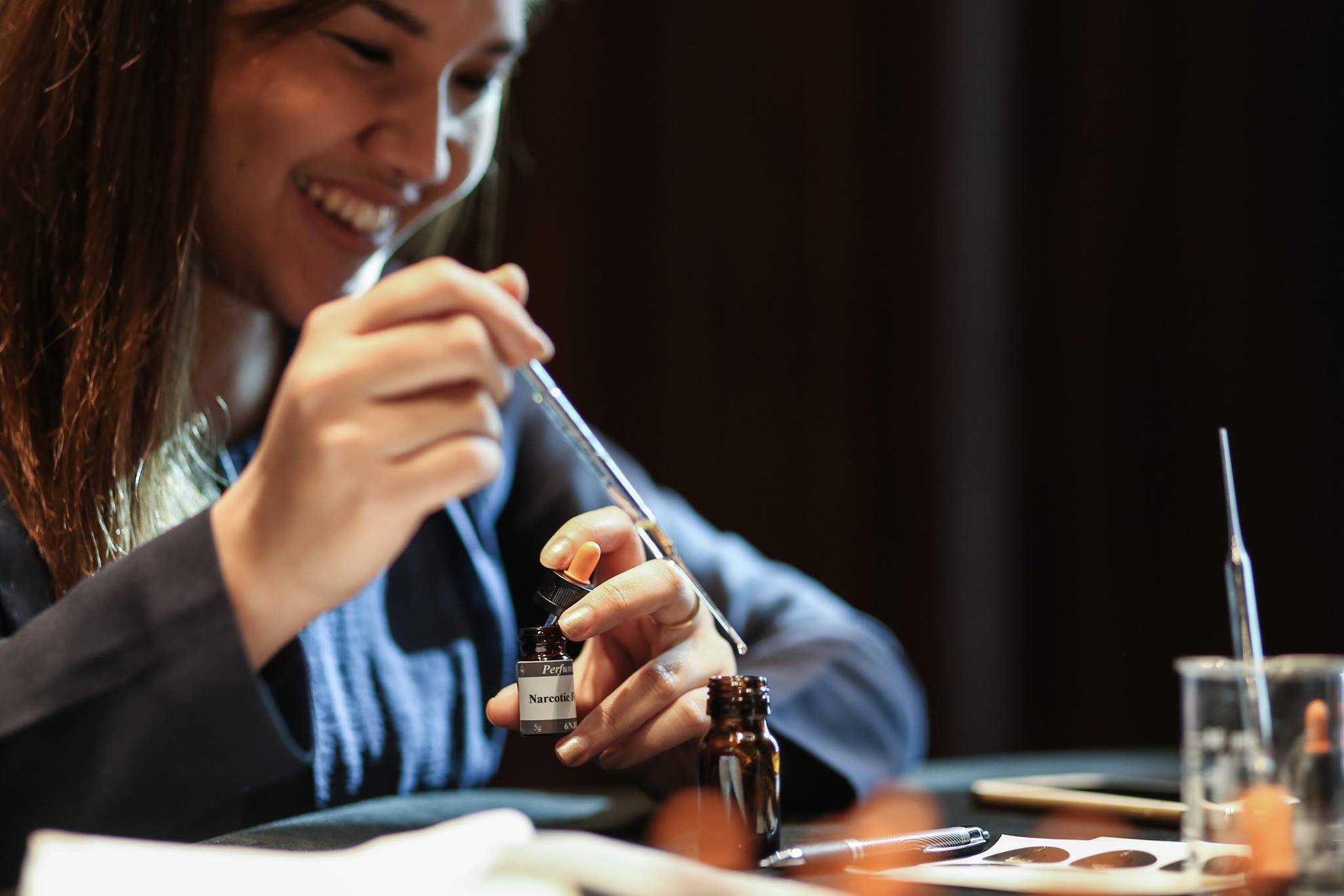 A participant smelling and blending fragrance materials with pipettes and bottles during an Artisan Valley workshop.